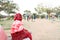 An old indian lady sitting on the bench and watching children playing in an open gym in a park