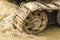 Old iron caterpillar in wet sand. Rusty steel wheels and caterpillar tape of a large bulldozer, tank, excavator, in damp sand and