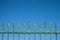 Old iron fence on blue sky - vintage wrought metal spikes -