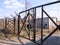 An old iron fence with a closed rusty gate prohibits travel to the territory of an abandoned technical station