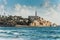 Old Jaffa city, old port and coastal line of Tel Aviv under sunset and lots of tourists are swimming and surfing at the