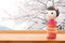 Old Japanese girl doll on wood table and blurred cherry blossom background