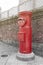 Old Japanese postbox stands beside a street in front of brick wall in a city of Japan with Japanese language translated as Post