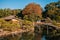 Old Japanese tea house in Okayama Korakuen park with wooden bridge and pond. Japan