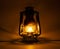 Old kerosene lamp glows on dark white background with soft shadows