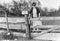 Old Lady Climbing Fence With Fishing Poles in Early 1900s