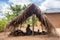 Old lady from Makonde tribe sitting in primitive kitchen and preparing local traditional meal