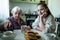 An old lady treats a little girl Breakfast, sitting at the table in his house.