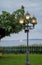 Old lamppost with glowing lanterns on the embankment in the evening