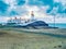 Old landscape lighthouse, white light tower with building for navigation on the thin spit of island