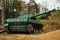 Old large green military tank is positioned in the middle of a vast grassy field