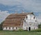 Old large white wooden barn with curved roof.