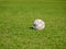 Old leak football/soccer ball abandoned on green grass field. Concept of sadness, hopeless and loneliness