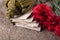 Old letters next to a bouquet of red carnations and a military bottle on a background of crumpled paper