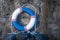 Old lifebuoy next to stone wall by the sea. Marine retro background