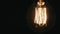 Old light bulb lights up continuously. On a black background, slightly swaying