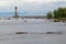 Old lighthouse on an island near the shore of a natural reservoir, river, sea with rocks, birds, gulls