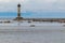 Old lighthouse on an island near the shore of a natural reservoir, river, sea with rocks, birds, gulls