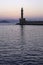 Old lighthouse in a quiet Harbor at sunset.