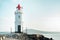 An old lighthouse with a red roof on the seashore. Seascape with copy space. Postcard from travel