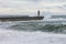 Old lighthouse in stormy sea waves