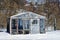 Old little greenhouse in a snowdrift on the street