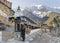 Old local woman spinning prayer wheels with a snow avalanche on Annapurna II mountain in the background  Upper Pisang  Nepal