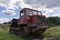 An old logging truck, rusty and abandoned in a field against the backdrop of a beautiful forest, as a symbol of the