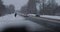 Old lonely grandmother with a crutch walks along the motorway in winter