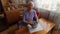 Old lonely woman sitting near the window in his house.