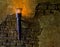 Old looking and lighted metal torch hanging on a stone wall, medieval interiors