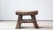 Old low Chinese oak stool in an empty room with white wall and floor. Traditional craft, handmade furniture. Generative AI