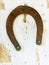 Old lucky horseshoe on aged white clay wall background.