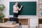 Old male teacher in front of blackboard