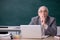 Old male teacher in front of blackboard