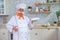 An old man with a bushy gray mustache in a chef's hat is cooking in the kitchen.