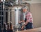 Old man dressed in apron working in modern brewery