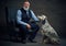 Old man dressed in suit posing on armchair and his dog