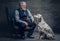 Old man dressed in suit posing on armchair and his dog