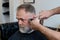 old man enjoying haircut by a master in a barbershop.  An old man gets a stylish haircut