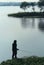 An old man fishing in the rural indian lake water