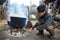 Old man fueling fire to boiling pots outdoor