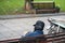 Old man with full leather hat reading book in park