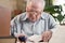 Old man in glasses writing from the books in the room