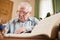 Old man in glasses writing from the books in the room