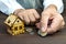 Old man hands and a model home with the coins on the table . The concept of mortgages and Bank loans. Poverty. Rental property. Ri