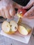 Old man hands peeling organic red Pink Lady apple outside over a bowl of apple slices