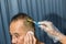 Old man having a hair cut by hairstylist using electrical battalion. men`s hairstyling and hair cutting with hair clipper in a bar