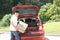 Old man loads his car`s suitcases