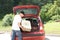 Old man loads his red car suitcases